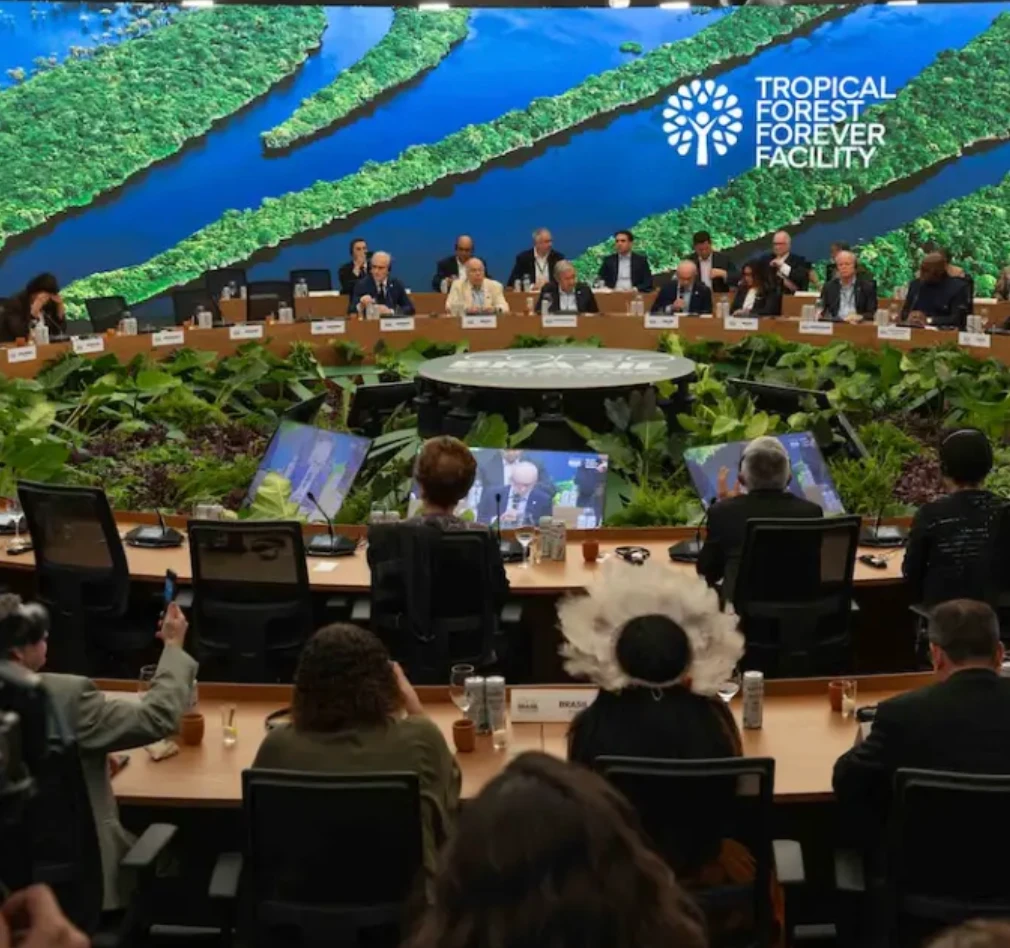 Delegates at a meeting with Tropical Forest Forever Facility signage.